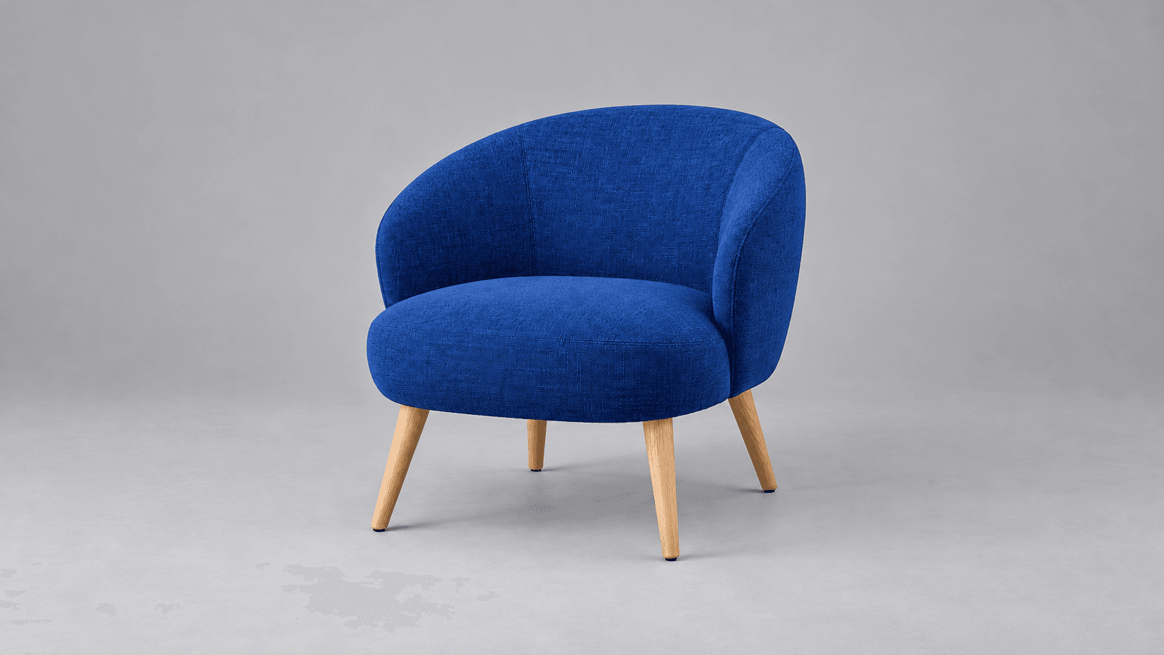 Cobalt-blue lounge chair photographed against a neutral studio backdrop